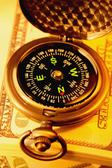 Сlose up compass on one hundred US Dollar bills. Selective focus.