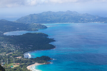 The view on the coastline with beaches and green hills, islands and blue Indian Ocean from the top of the mountain Morne. Mahe, the Seychelles