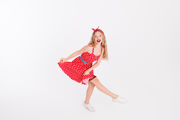 Plakat Cheerful young woman in a dotted red dress posing with a joyful dance movement on a white background