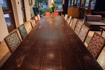 super long wooden table indoor with chairs covered with different fabric on the evening