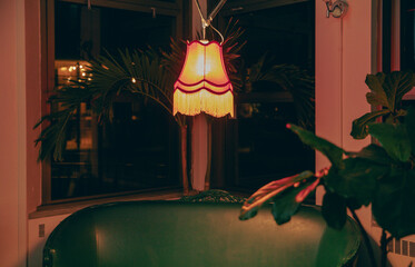 view of a hanging lamp over a sofa providing an orange warm light in a dark and moody room