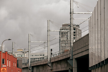 street view of a bridge with an electric railroad on top on an overcast day in the city