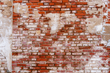A weathered and textured brick wall with peeling plaster and red bricks, capturing age and wear