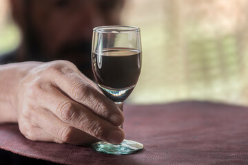 Man in the shadows holding a glass of red wine
