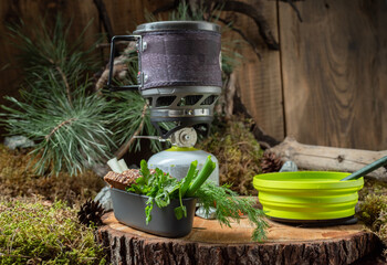 Composition of food and dishes on the table. Tourist kitchen on the background of a tree and spruce. Tourist food and dishes.