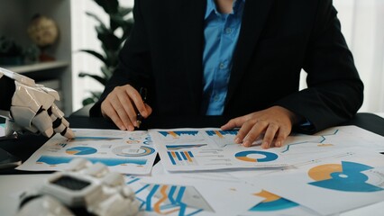 A business professional examines various graphs and data charts while utilizing futuristic technology in a modern office environment. The setting emphasizes innovation.Noogenesis