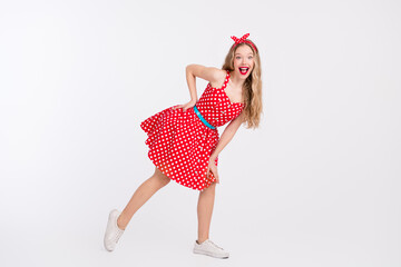 Cheerful woman in polka dot retro dress dancing on white background showing lively style and...