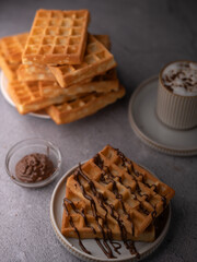 photo Delicious golden brown waffles drizzled with decadent chocolate syrup alongside a steaming...