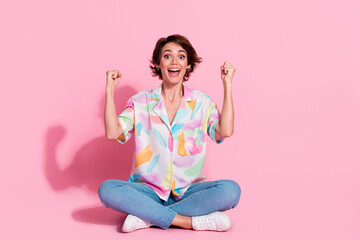 Full size photo of pretty young lady raise fists empty space wear shirt isolated on pink color...