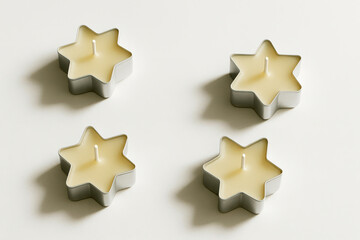 Fototapeta premium Star-shaped candles arranged on a white surface 