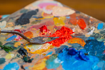 Old used palette knife, palette with multi-colored spots of oil or acrylic paint in an artist's...