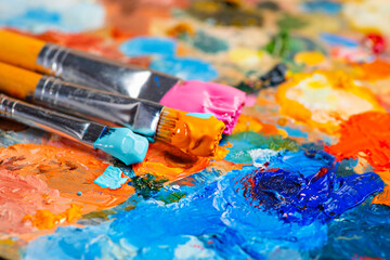 Old used brushes in an artist's studio, palette with multi-colored spots of oil or acrylic paint