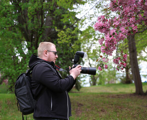 Male Photographer Capturing Spring Blossoms Outdoors with DSLR Camera

