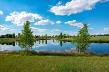 Great Lawn Park, part of the Westerly Wetlands Ecosystem, is a scenic tranquil park in Denver, Colorado that includes a tall pointy sundial, visible in the distant background.