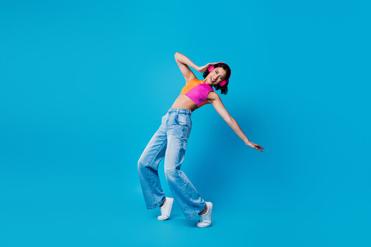 Young happy woman in fashionable summer outfit posing dynamically against vibrant blue background showcasing happiness