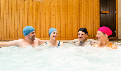 A group of four people between the ages of 20 and 40 are leaning against a thermal bubble pool. The concept of happy friends in a round bubble pool.