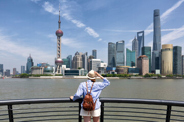woman traveler visiting in Shanghai, China. Female Tourist with backpack sightseeing Shanghai view of Lujiazui in The Bund of Shanghai. Vacation concept
