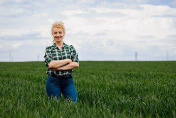 Adult female farmer standing in green wheat field looking at camera. © Zoran Zeremski