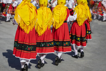 Bulgarian folk dance. Group of women in traditional red skirts and yellow scarves performing folk...