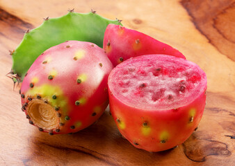 Opuntia fruit or prickly pear cactus and opuntia cut in half isolated on wooden table.