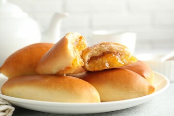 Tasty baked patties with orange jam on light grey table, closeup