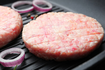 Fresh raw patties for burger and spices in frying pan, closeup