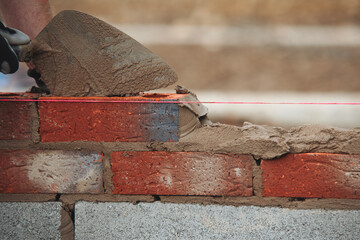 Close-up of skilled bricklayer working on construction site laying bricks for wall construction