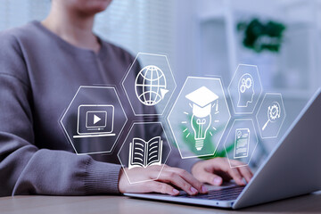 Online education and e-learning concept. A person use a laptop with icons representing online...