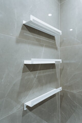 Three meticulously organized white shelves are elegantly suspended against a beautifully tiled wall...