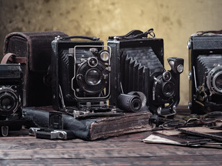 Old cameras are arranged in a composition on a wooden background, on a table.