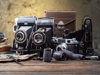 Old cameras are arranged in a composition on a wooden background, on a table.