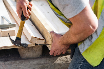 Close-up of hands of builder joiner using plywood and timber to asseble shutter panel for concrete...