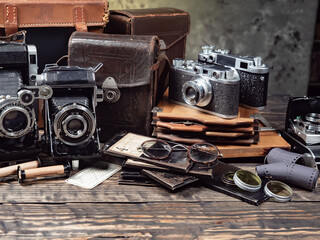 Old cameras are arranged in a composition on a wooden background, on a table.