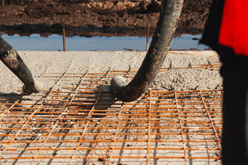Construction worker pouring concrete onto reinforcing mesh at a building site