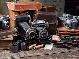 Old cameras are arranged in a composition on a wooden background, on a table.
