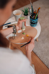 Artist squeezing paint onto palette and holding brush, preparing to paint