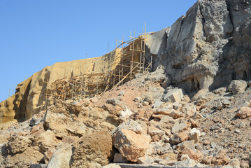 Wooden scaffolding to strengthen the seashore. Work on a cliff near the sea.