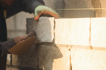 Close-up of skilled bricklayer working on construction site laying bricks for wall construction