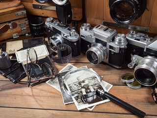 Old cameras are arranged in a composition on a wooden background, on a table.