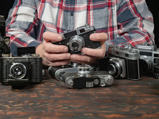 An elderly collector studies old cameras. Close-up.