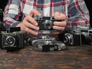 An elderly collector studies old cameras. Close-up.