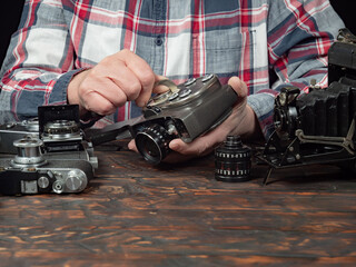 An elderly collector studies old cameras. Close-up.