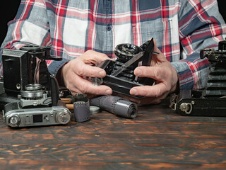 An elderly collector studies old cameras. Close-up.