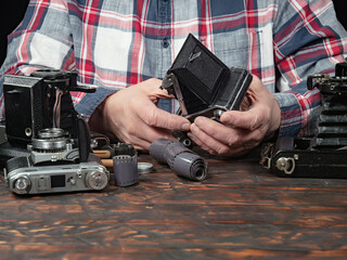 An elderly collector studies old cameras. Close-up.
