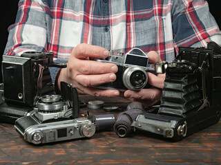 An elderly collector studies old cameras. Close-up.