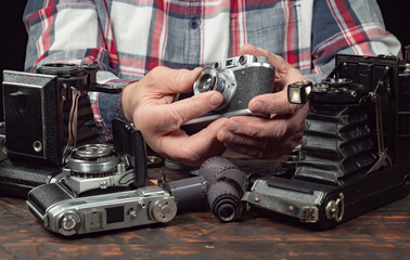 An elderly collector studies old cameras. Close-up.