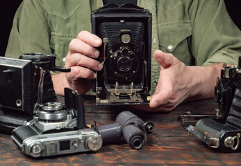 An elderly collector studies old cameras. Close-up.
