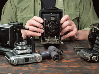 An elderly collector studies old cameras. Close-up.