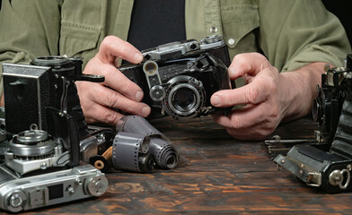 An elderly collector studies old cameras. Close-up.
