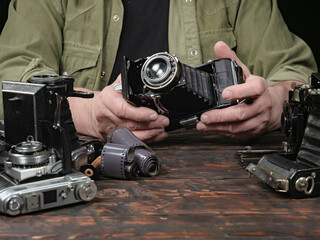 An elderly collector studies old cameras. Close-up.